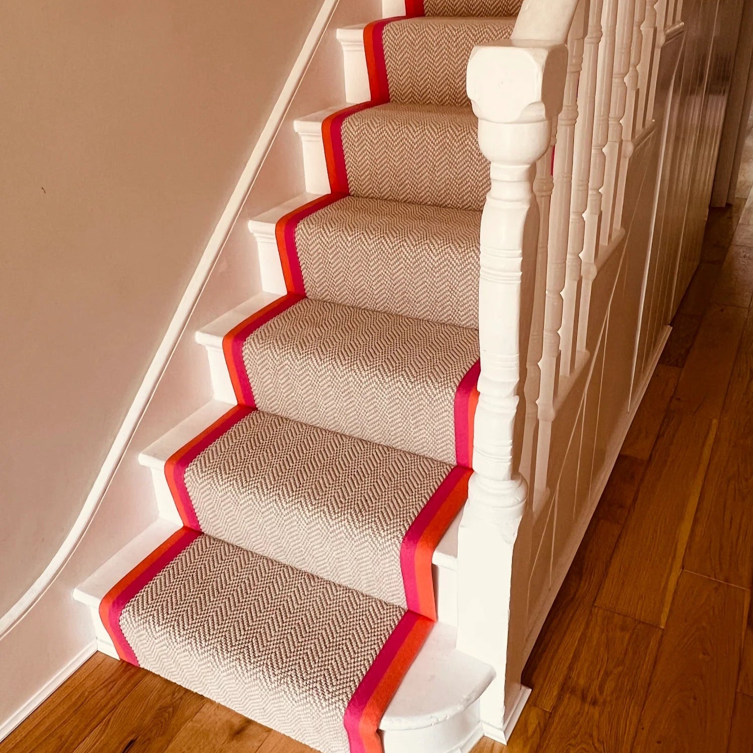 Staircase with beige carpet and red border on wooden floor